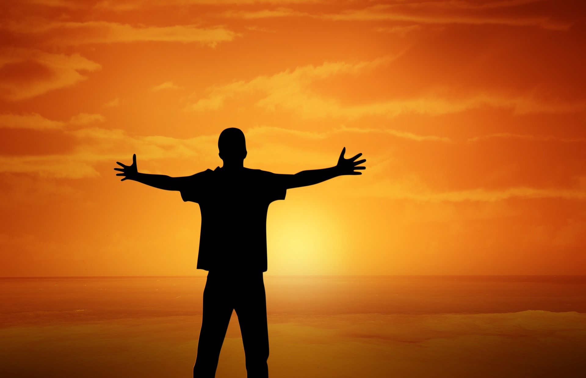 Man standing in front of dawn sun with arms stretched as if to embrace life!