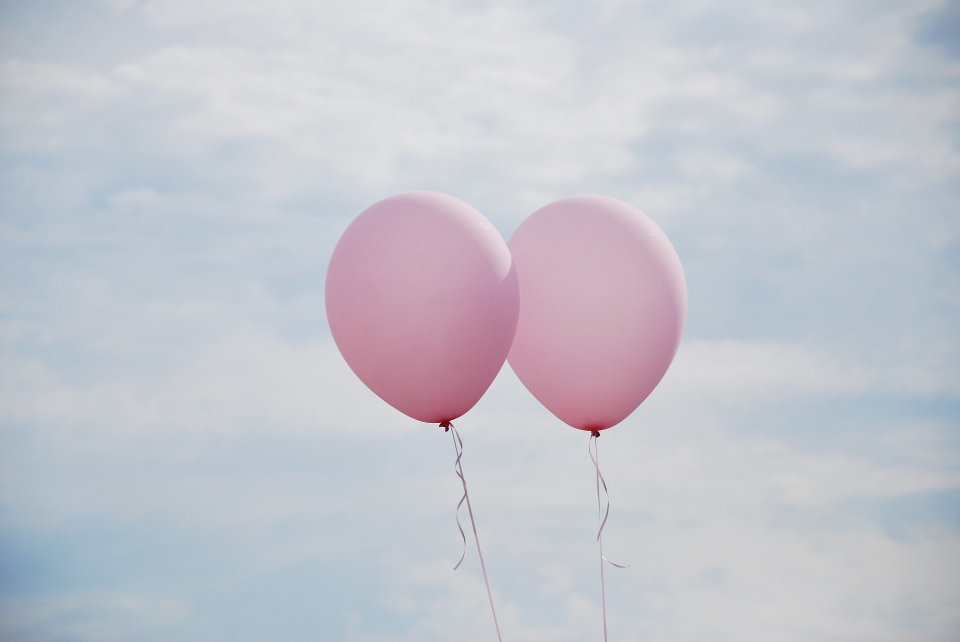 Two pink balloons flying high in the sky! 